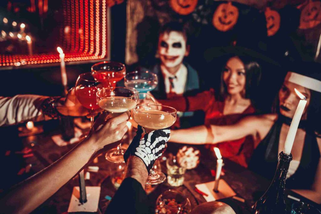 Friends at a Halloween party at Plume in Houston, TX, toasting with glasses in festive costumes.
