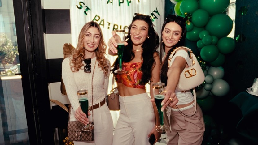 Three women at Plume in Houston, TX, joyfully sipping green cocktails at a birthday celebration.